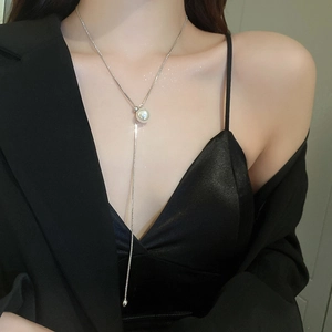 Close-up of a silver pearl adjustable necklace worn by a model in elegant black attire