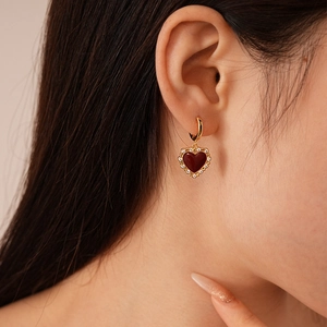 Close-up of vintage red enamel heart earrings with gold plating and zircon inlay on model