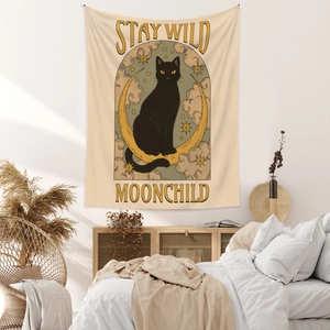 Detail of bohemian tapestry featuring a black cat on a crescent moon with text Stay Wild