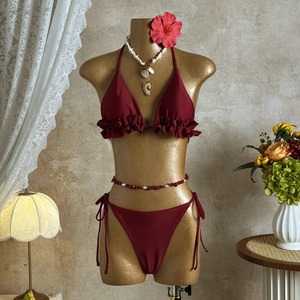 Detailed view of maroon ruffled bikini on mannequin with tropical floral background
