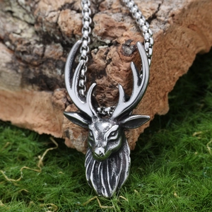 Macro shot of silver deer head pendant with vintage texture on a rustic wooden background