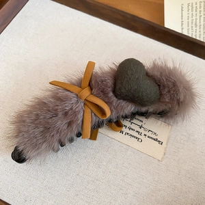 Detail of plush faux fur hair claw clip featuring heart charm and mustard yellow bow