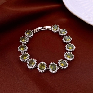 Detail of oval emerald zircon halo bracelet with folding clasp on silk background