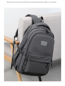 Detail view of dark grey nylon backpack featuring multiple zip pockets and soft padded straps