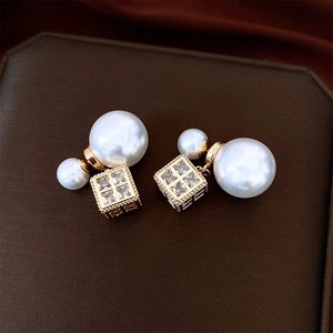Detail of gold double pearl earrings featuring a micro-set cubic pendant on silk
