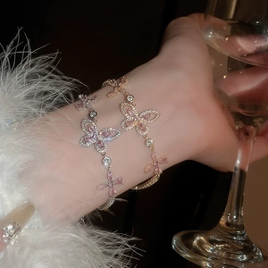 Detailed view of silver and rose gold butterfly bracelets with pink cubic zirconia