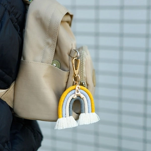 Pendentif arc-en-ciel tissé avec lettre A et pompons sur un sac à dos beige