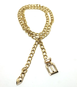 Close-up of golden metal chain belt with square buckle and delicate heart pendant detail