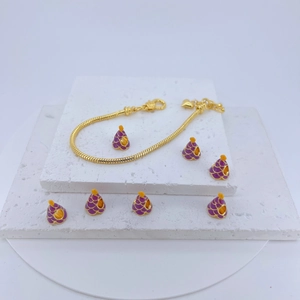 Gold snake chain bracelet with purple and yellow enamel cone charms on white stone