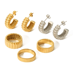 Detailed view of 18K gold and silver stainless steel gear rings and C-shaped earrings