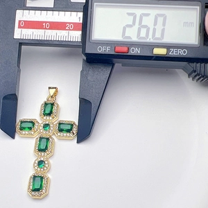 Detailed dimension measurement of zircon cross pendant showing 26mm width with caliper