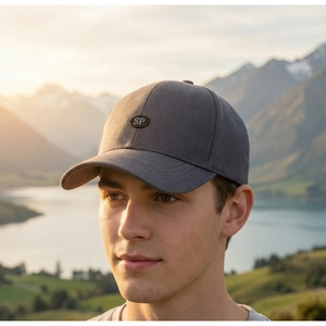 Man wearing a dark grey baseball cap with SP logo against a mountain lake sunset background