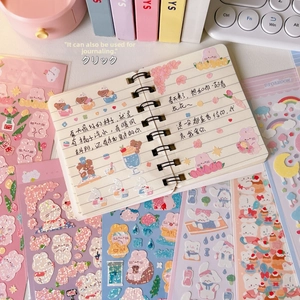 Macro shot of cute cartoon bear stickers with glitter effect on a coil notebook
