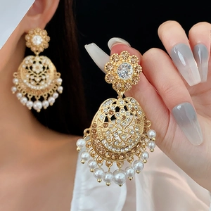 Vintage gold drop earrings with acrylic diamonds and pearls shown on a model