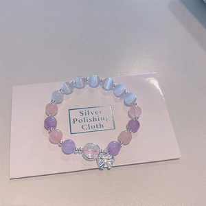 Detail of beaded bracelet with cat eye stones, silver butterfly charm on polishing cloth