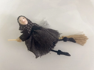 Halloween witch doll hanging decoration in black mesh skirt on a rustic broomstick