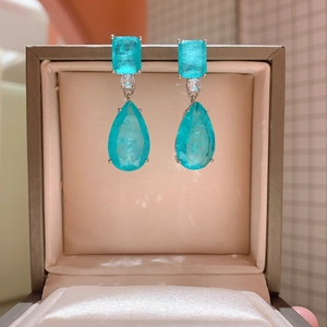 Close-up of pear-shaped blue gemstone drop earrings with rectangular top in jewelry box