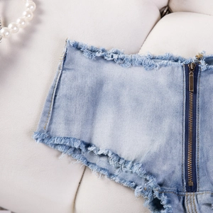 Detailaufnahme der Jeans-Shorts mit Metallreißverschluss und stark ausgefransten Kanten