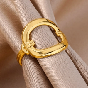 Macro view of gold D-shape geometric ring on champagne silk showing polished texture