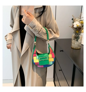Close-up of green crescent bag featuring colorful patch patterns and gold metal buckles