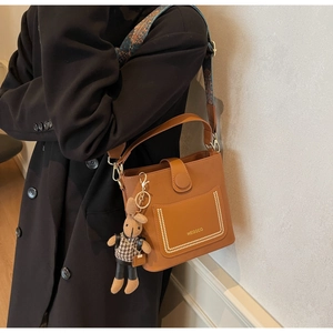 Detail of brown leather bucket bag with vintage ethnic strap and cute rabbit pendant