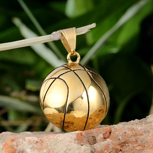 Detailed close-up of golden basketball pendant on a branch with natural light