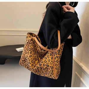 Detailed close-up of leopard print fabric texture and durable brown shoulder straps on tote