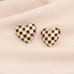 Detailed view of heart-shaped checkerboard earrings with gold plating and enamel