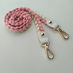 Detail of pink and white woven shoulder strap with gold metal buckles and leather ends
