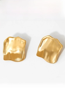 Detail showing irregular gold square earrings with a minimalist hammered metal texture