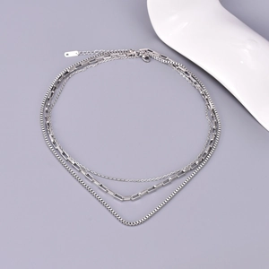 Macro detail of triple-layer stainless steel necklace with various chain textures