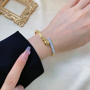 Elegant gold titanium steel open bangle featuring polished beads and a paved crystal bar