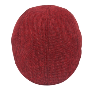 Close-up of reddish-brown flat cap showing coarse wool texture and stitching details