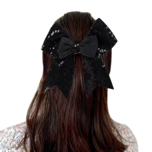 Detail of a black sequined bow hair clip worn on dark hair for elegant styling