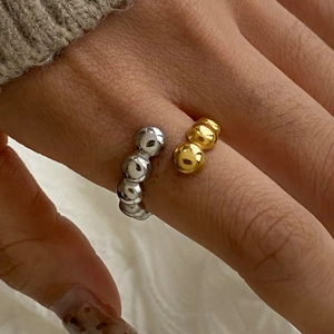 Close-up of a two-tone gold and silver beaded open ring in polished stainless steel