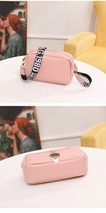 Pink woven camera bag with stylish wide fabric strap and cat charm detail