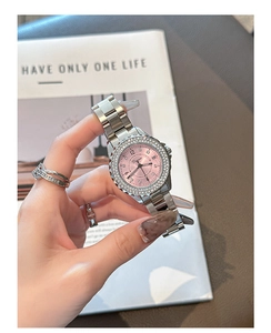 Detail of a pink dial watch with crystals and silver stainless steel strap on wrist