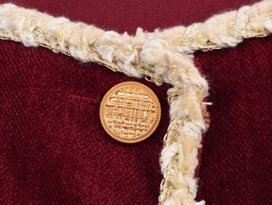 Close-up of wine red chenille dress with gold chain trim and pearl-style metal button