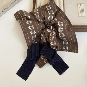 Details eines karierten Retro-Haargummis mit marineblauer Schleife auf Holztablett