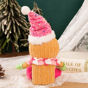 Plush gingerbread man Christmas ornament with pink hat and striped scarf on table