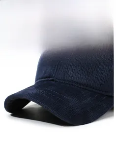 Detail of navy blue corduroy baseball cap with metal logo and firm brim texture
