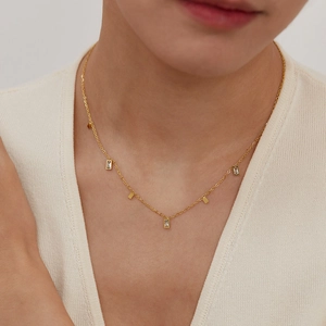 Close-up of elegant gold chain necklace with rectangular zircon pendants on a model