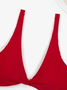 Dettaglio del top bikini rosso allacciato al collo con scollo a V e nodo frontale