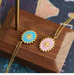 Detail of vintage enamel sun pendants in sky blue and pink on 18K gold plated chains
