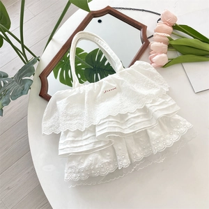 Dettaglio della borsa tote bianca con balze di pizzo e ricami rossi decorativi