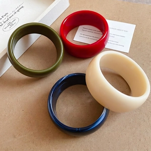 Set of four acrylic geometric round bangles in olive, red, navy blue, and cream