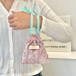 Detail of pink lace drawstring bag with mint green handles and velvet texture