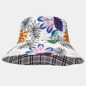 Detail showing reversible bucket hat with tropical leaf print and plaid patterns
