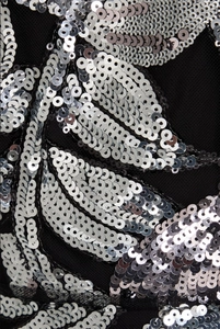 Détail de paillettes argentées et broderie florale sur tulle noir de robe de soirée
