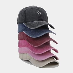 Detailed stack of washed cotton baseball caps with double heart embroidery in various colors